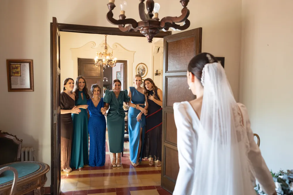 La novia entrando en la habitación donde la esperan sus amigas